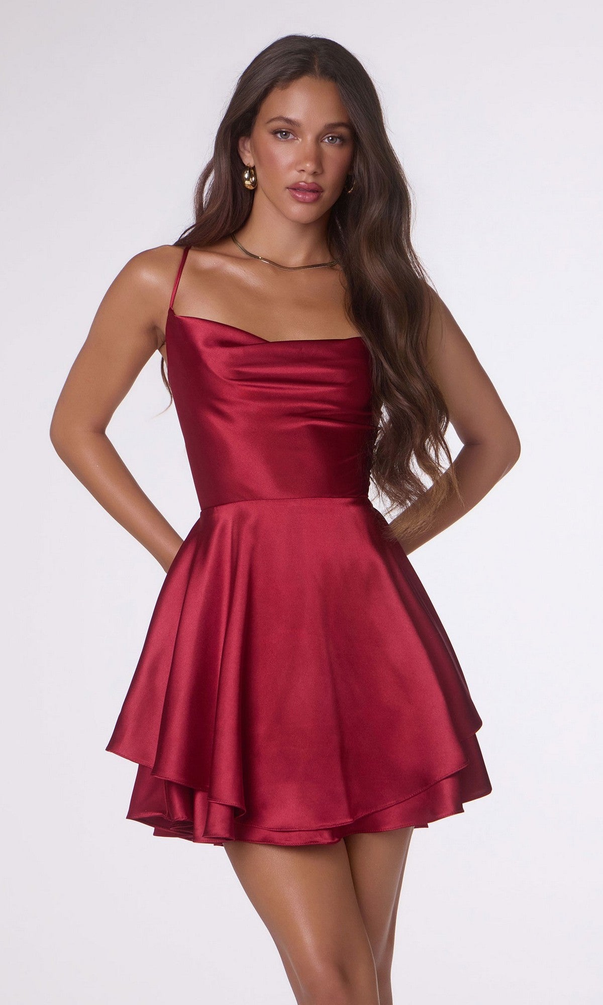A woman wearing the Short Homecoming Dress: Amoris T616 in burgundy, featuring a sleeveless satin design, cowl neckline, open back, and flared A-line skirt, stands against a plain light background.